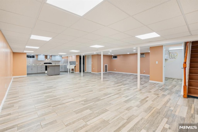 basement featuring a paneled ceiling and light hardwood / wood-style floors