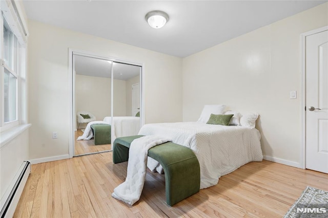 bedroom featuring a baseboard heating unit, a closet, and hardwood / wood-style flooring