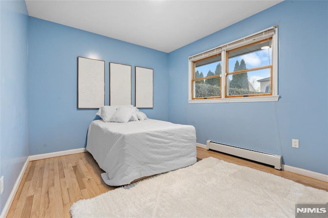 bedroom with a baseboard radiator and hardwood / wood-style floors