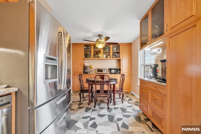 kitchen with ceiling fan, stainless steel fridge, and light stone countertops