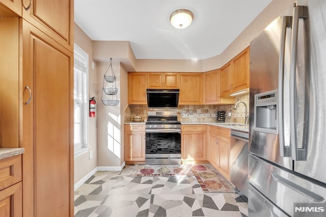 kitchen featuring stainless steel appliances, light brown cabinets, decorative backsplash, and sink