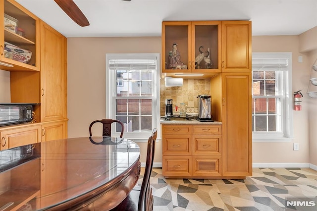 interior space with light stone counters, ceiling fan, and backsplash