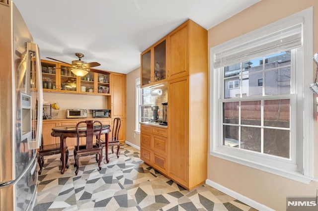 kitchen with ceiling fan, a wealth of natural light, and stainless steel fridge with ice dispenser