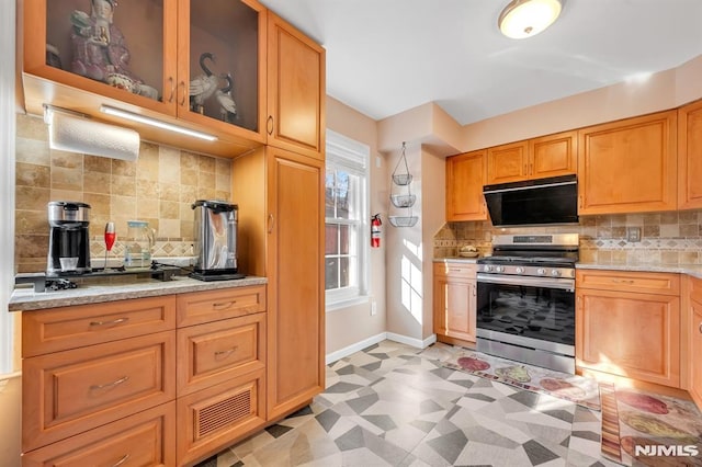 kitchen with light stone counters, stainless steel gas range, and backsplash