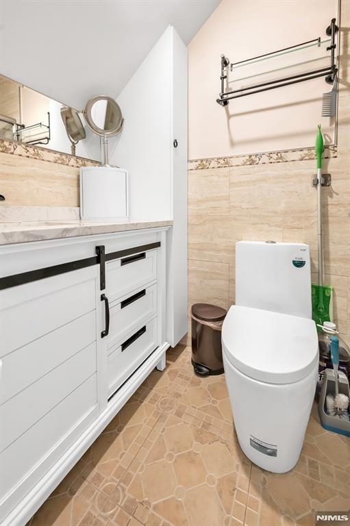 bathroom featuring tile walls and toilet