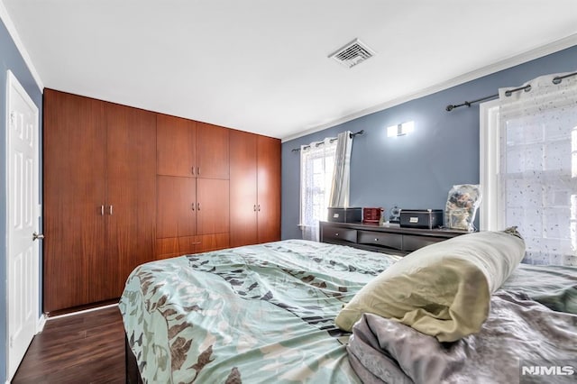 bedroom with ornamental molding, dark wood-type flooring, and a closet