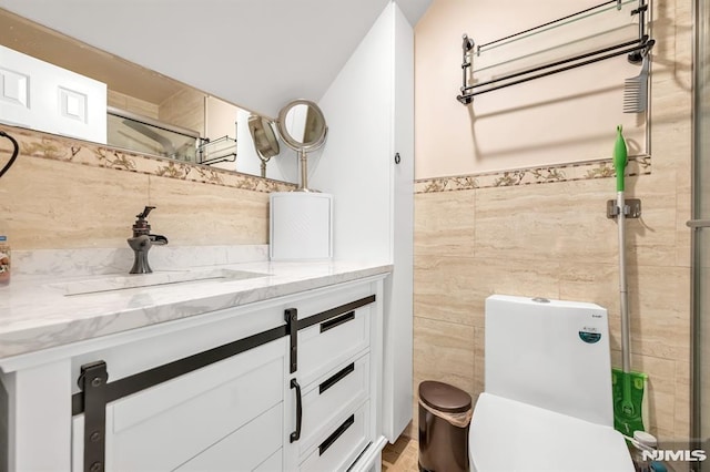 bathroom featuring tile walls, a tile shower, vanity, and toilet