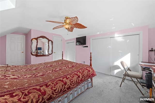 carpeted bedroom with ceiling fan, two closets, and lofted ceiling