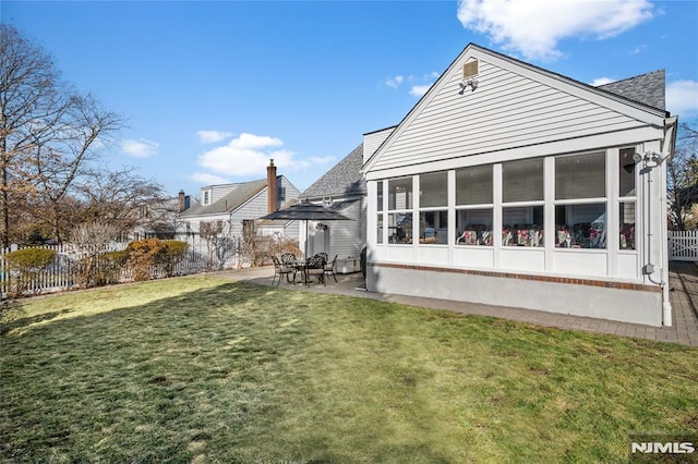 rear view of house featuring a lawn, a sunroom, and a patio