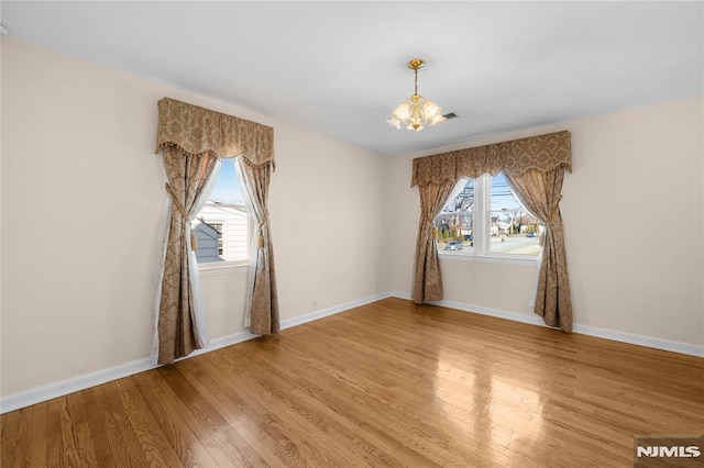 unfurnished room with a notable chandelier and hardwood / wood-style floors