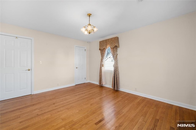 spare room with a chandelier and light hardwood / wood-style floors