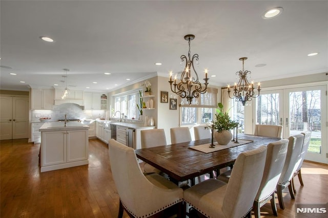 dining area featuring light hardwood / wood-style flooring, a chandelier, french doors, ornamental molding, and sink