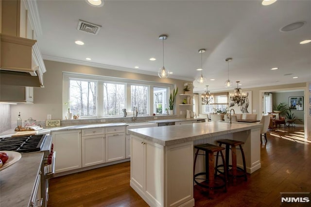 kitchen with hanging light fixtures, dark hardwood / wood-style floors, a kitchen island, white cabinets, and sink