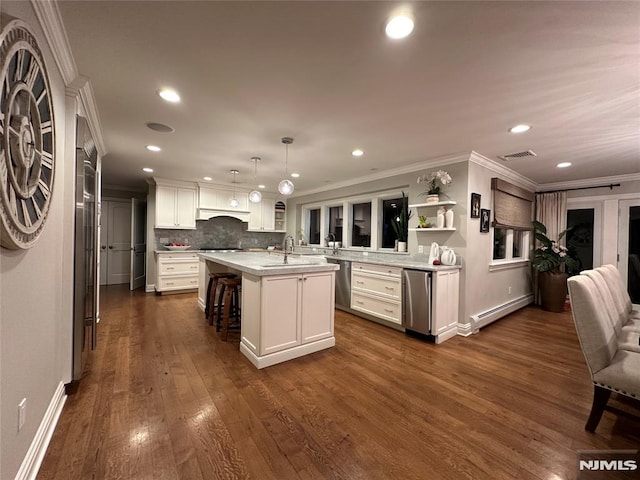 kitchen featuring hanging light fixtures, an island with sink, a kitchen bar, a baseboard radiator, and sink