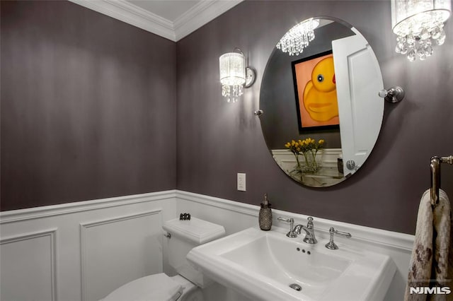 bathroom featuring sink, crown molding, a chandelier, and toilet