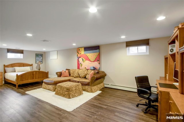 bedroom with a baseboard heating unit, multiple windows, and dark hardwood / wood-style floors