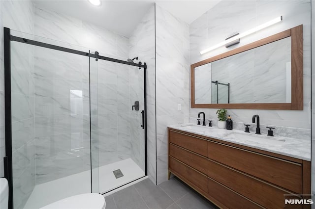 bathroom with tile walls, a shower with shower door, toilet, tile patterned floors, and vanity