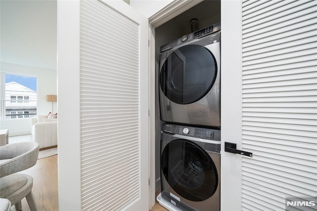 laundry area with stacked washer and clothes dryer and light hardwood / wood-style floors