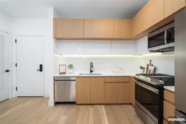 kitchen featuring appliances with stainless steel finishes, light hardwood / wood-style floors, sink, and light brown cabinets