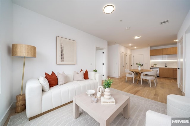 living room with sink and light hardwood / wood-style flooring