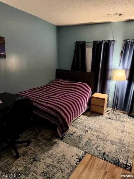 bedroom with a textured ceiling and hardwood / wood-style floors