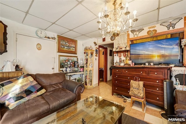 tiled living room featuring a chandelier and a drop ceiling