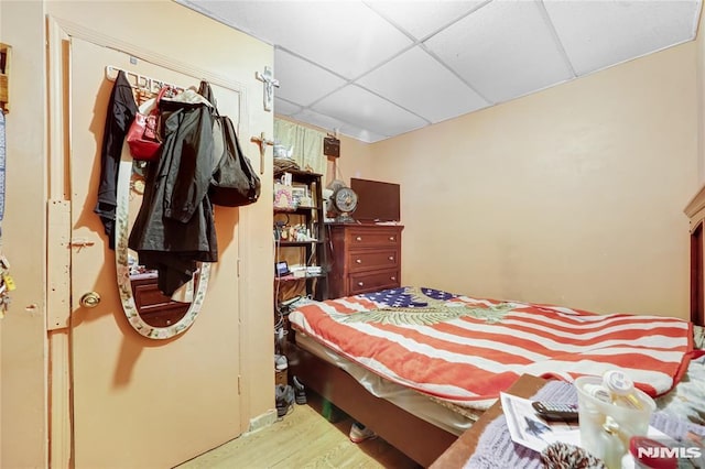 bedroom with light wood-type flooring and a drop ceiling