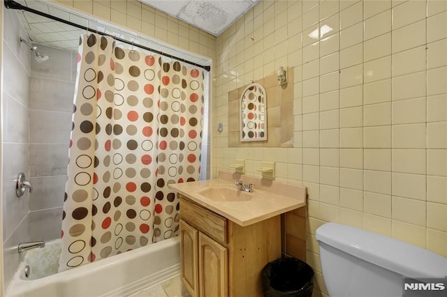 full bathroom featuring tile walls, toilet, vanity, and shower / bath combination with curtain