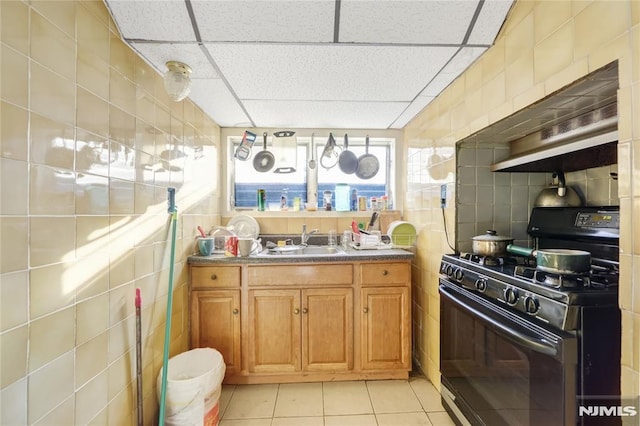 kitchen with sink, tile walls, black range with gas cooktop, a drop ceiling, and light tile patterned floors