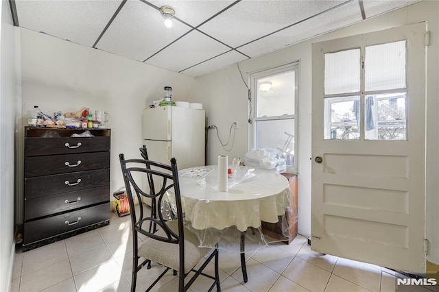 dining space with light tile patterned floors and a drop ceiling