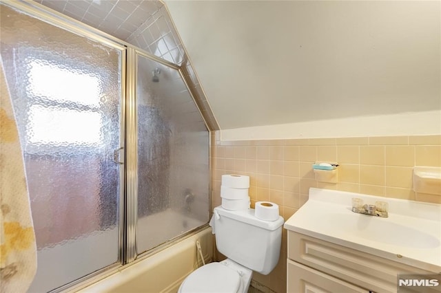 full bathroom featuring bath / shower combo with glass door, toilet, vanity, and tile walls