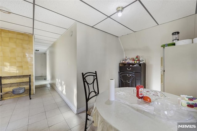 dining space featuring a paneled ceiling and light tile patterned floors