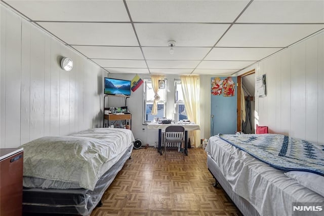 bedroom featuring wood walls and dark parquet floors