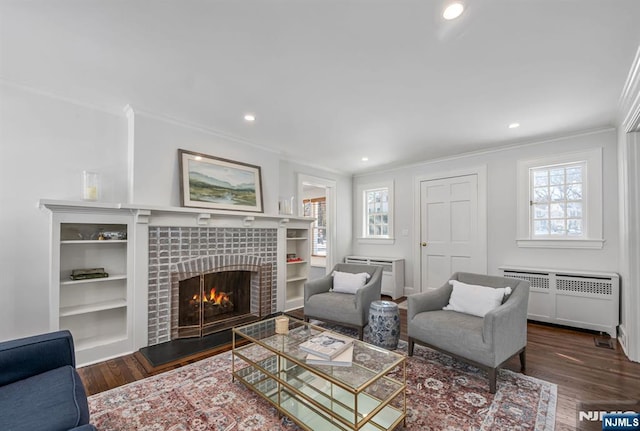 living room with crown molding, radiator heating unit, dark wood-type flooring, and a tile fireplace