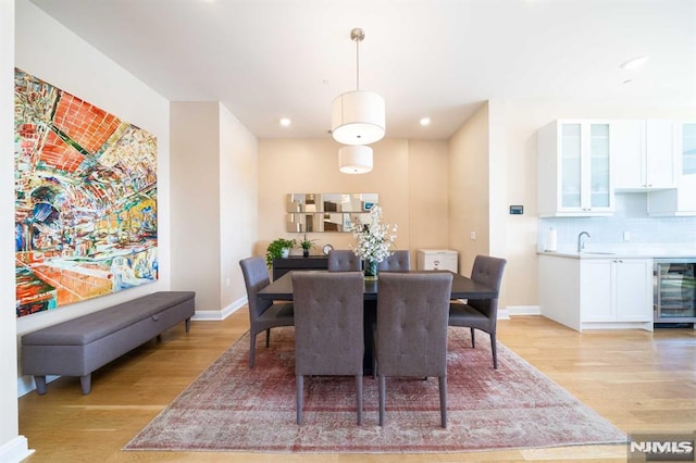 dining area with sink, light hardwood / wood-style flooring, and beverage cooler