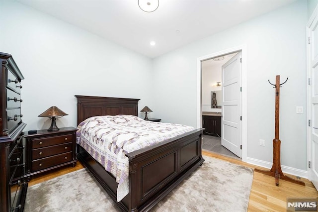 bedroom with light wood-type flooring and ensuite bathroom