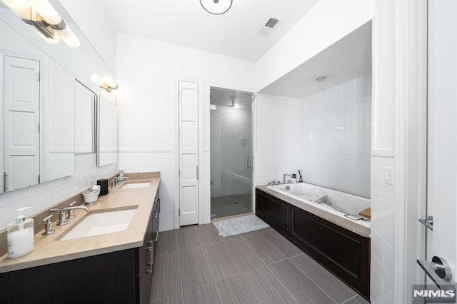 bathroom with tile walls, vanity, and independent shower and bath