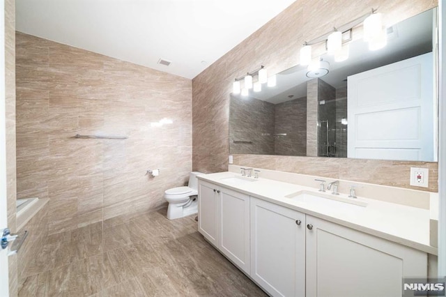 bathroom featuring toilet, a shower, vaulted ceiling, tile walls, and vanity