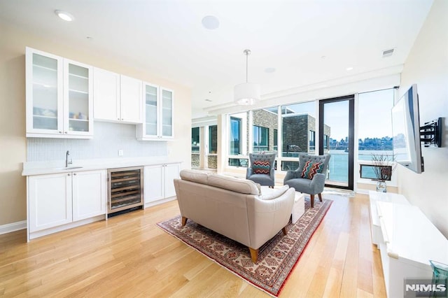 living room featuring light wood-type flooring, indoor wet bar, and wine cooler