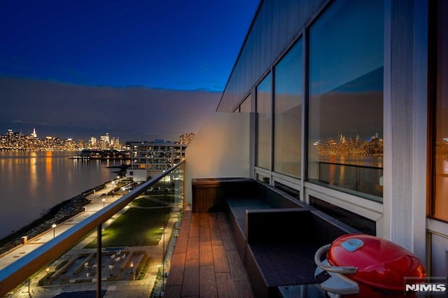 balcony at dusk featuring a water view