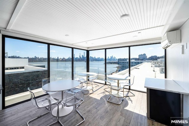 sunroom featuring a wall mounted air conditioner, a healthy amount of sunlight, and a water view