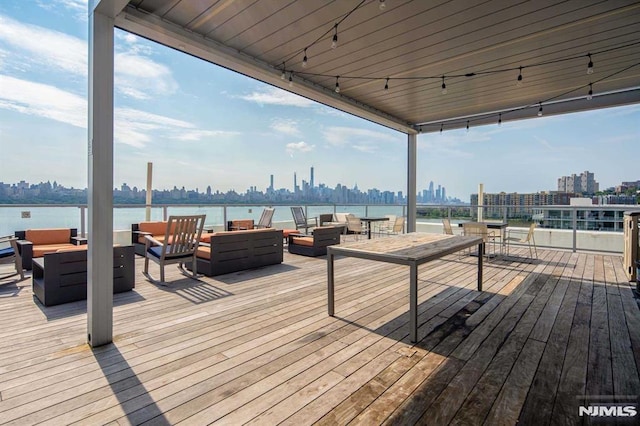 wooden deck with a water view and outdoor lounge area