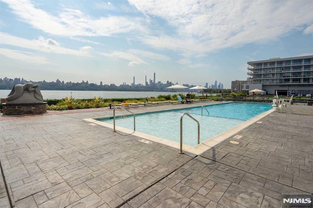 view of pool featuring a patio area and a water view