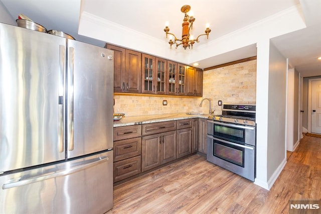 kitchen featuring sink, light hardwood / wood-style flooring, backsplash, stainless steel appliances, and light stone countertops