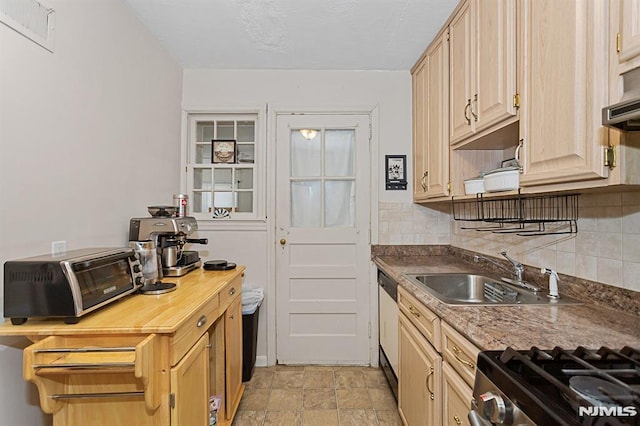 kitchen with a toaster, decorative backsplash, dark countertops, stone finish floor, and a sink