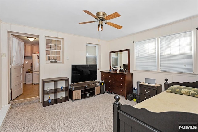 bedroom with light carpet, freestanding refrigerator, and a ceiling fan