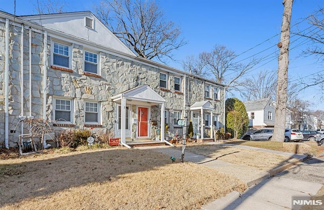 townhome / multi-family property with stone siding and a front lawn