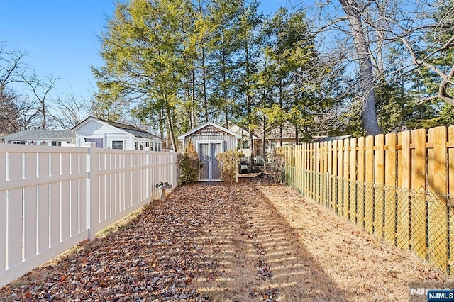 view of yard with a fenced backyard, a shed, and an outbuilding