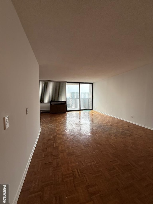 spare room with dark parquet flooring and a wall of windows