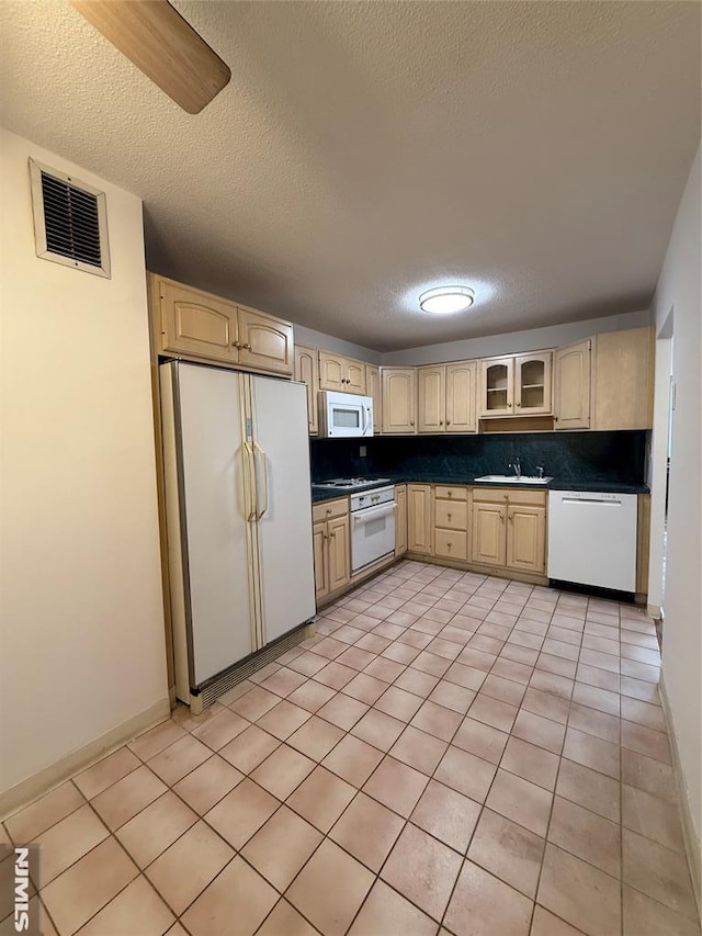 kitchen featuring white appliances, a textured ceiling, light tile patterned floors, and tasteful backsplash